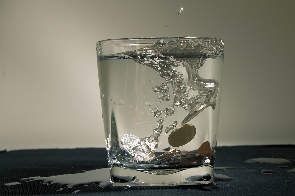 coins dropping into a glass of water