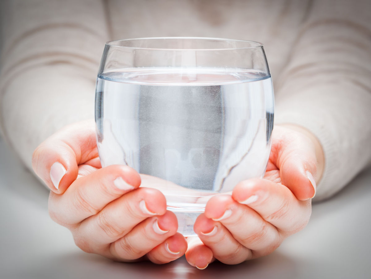 A close-up of a person's hands holding a cup of water.